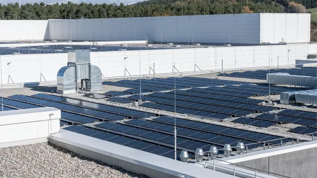 Flat roof with multiple rows of solar panels and ventilation units in the background.