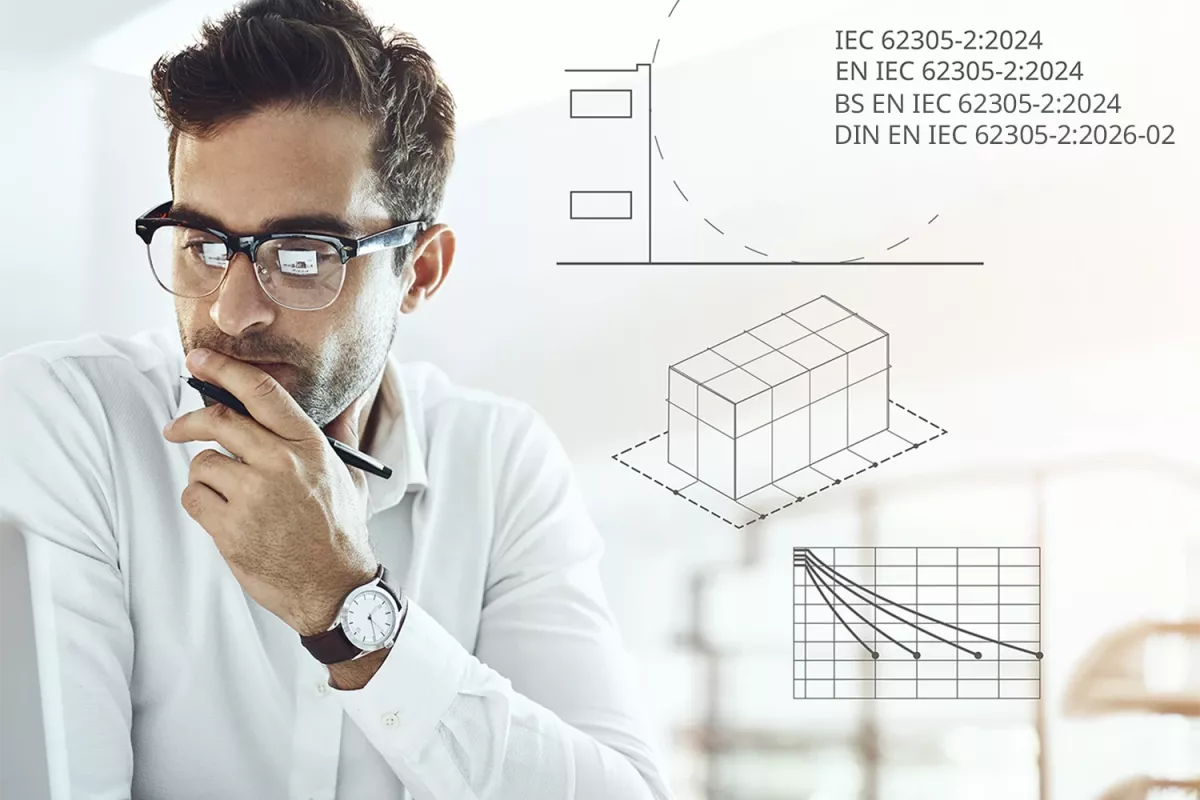 Man in glasses working at a laptop, holding a pen thoughtfully, with technical diagrams and IEC 62305-2:2024 graphics overlaid in the background.